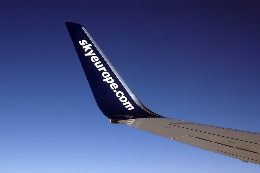 Winglet dopravného lietadla Boeing 737 s bielym nápisom skyeurope.com na tmavomodrom pozadí a modrou oblohou